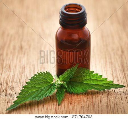 Nettle Leaves With Extract In A Bottle On Wooden Surface