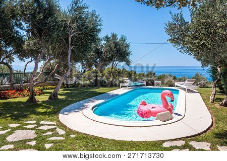 Pink Flamingo Waterbed In Swimming Pool With Mediterranean Sea In The Background