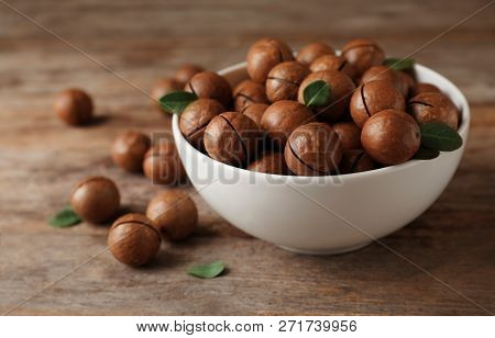 Bowl With Organic Macadamia Nuts And Space For Text On Wooden Background