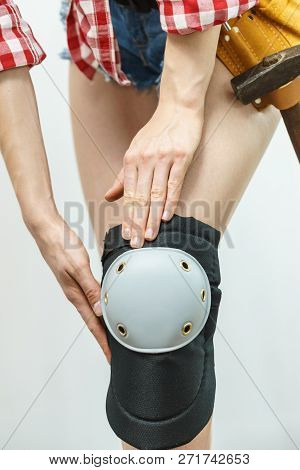 Unrecognizable Woman Wearing And Adjusting Her Safety Knee Protectors Pads. Safe Workwear During Con