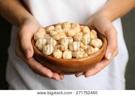 Woman Holding Bowl With Shelled Organic Macadamia Nuts, Closeup