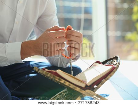 Muslim Man With Koran And Misbaha Praying Indoors, Closeup