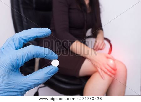 Business Girl In The Office Sits In A Computer Chair And Holds Her Knee, Pain And Inflammation In Th