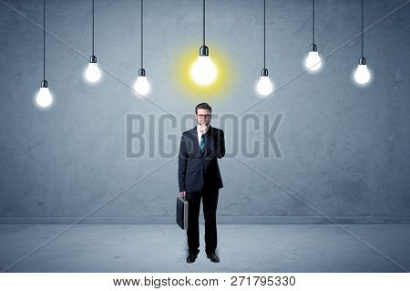Handsome businessman in an empty space with bulbs above and uninspired face