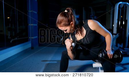 A Girl Performs A Concentrated Bench Press Sitting With The Help Of Dumbbells.