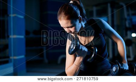 A Girl Performs A Concentrated Bench Press Sitting With The Help Of Dumbbells.