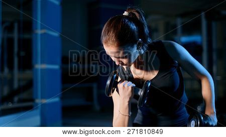 A Girl Performs A Concentrated Bench Press Sitting With The Help Of Dumbbells.
