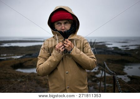 Cold And Shievering Young Woman In Raincoat