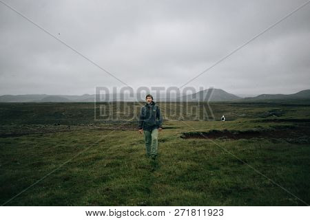 Hiker Or Traveller Walks In Green Field In Iceland