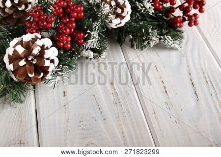 Spruce Branches, Cones And Red Berries On A White Wooden Background. Background For Christmas And Ne
