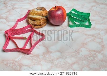 Sweet Bun, Apple And Measuring Tapes. Healthy And Unhealthy Food Concept - Red And Green Tape.