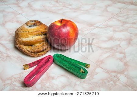 Sweet Bun, Apple And Measuring Tapes. Healthy And Unhealthy Food Concept - Red And Green Tape.