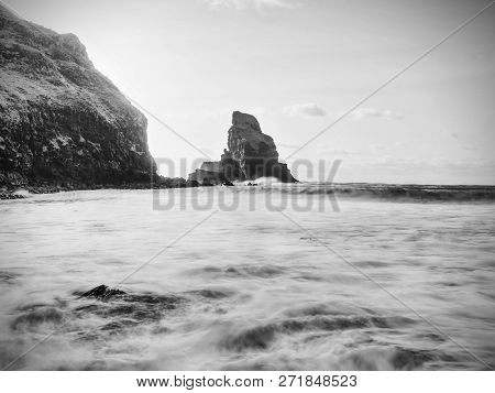 Beautifully Shaped Black Boulders And A Dramatic Fiery Sunset And A Stony Beach