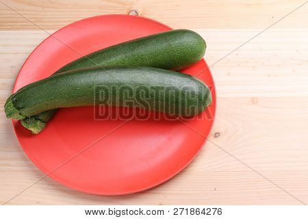 Fresh Zucchini On A Red Plate And Wooden Background. Healthy And Healthy Food.