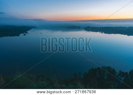 Mystical View From High Shore On Broad River. Riverbank With Forest Under Mist. Early Haze Above Tre