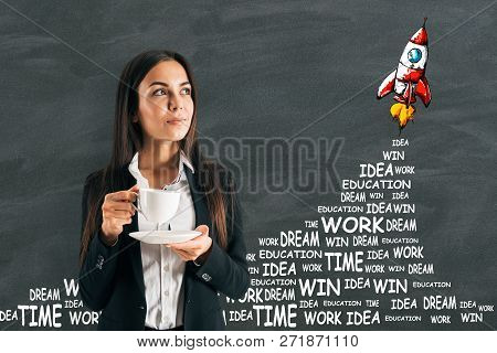 Portrait Of Attractive Young Euopean Businesswoman Drinking Coffee On Chalkboard Wall Background Wit