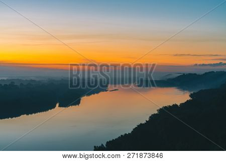View From High Shore On River. Riverbank With Forest Under Thick Fog. Gold Dawn Reflected In Water. 