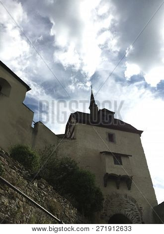 A Tower Of A Castle In Germany Rises Into An Overcast Sky. There Are Few Windows In The Tower Which 