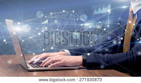 Businessman typing on laptop with linked reports charts grapghs around