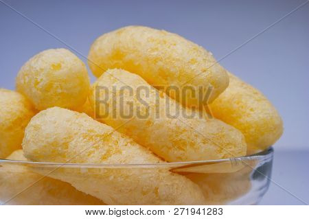 Zoomed Corn Puffs In A Glass Bowl. Crunchy Flavored Puffed Snacks. Party, Movie Snacks.