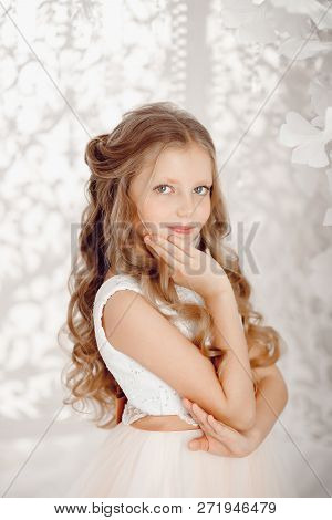 Portrait Of Blond Beauty Little Girl 10 Years Old. White Lush Dress Resembles Ballerina, Merges With