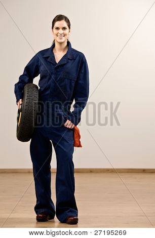 Lastiği tutan coveralls gülümseyen mekanik