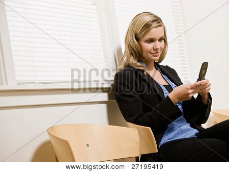 Podnikatelka textových zpráv na mobilní telefon v kanceláři čekárnu