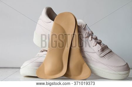 Orthopedic Insoles With Sports Shoes Isolated On White Wooden Board. Foot Care Conception.