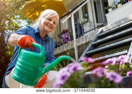 Senior woman watering plants in her garden
