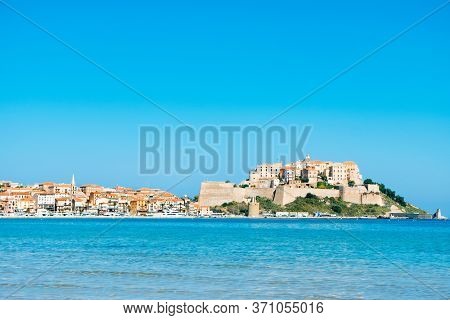 a panoramic view of Calvi, in Corsica, France, with its famous citadel on the rigth on the top of a promontory, and the Mediterranean sea in the foreground