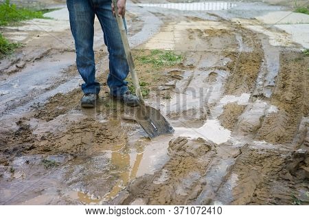 A Man Standing With Spud On The Muddy Road, Outdoor Cropped Shot