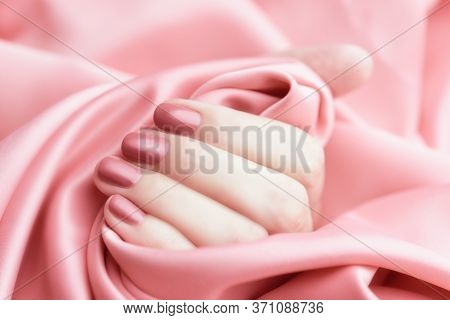 Female Hand With Pale Pink Manicure On A Pink