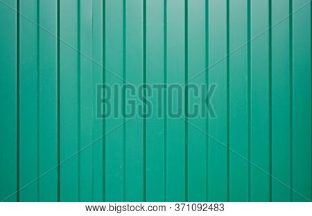 Galvanized Iron Fence With Corrugated Vertical Stripes Of Green As Fence Wall. Vertical Narrow Lines