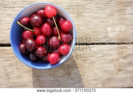 Ripe Black Cherries With Water Drops In A White Ceramic Bowl With A Blue Border On A Wooden Table Ba