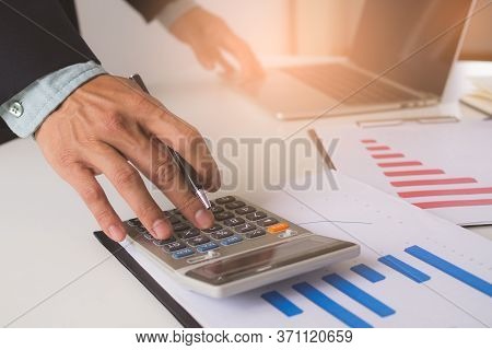 Close Up View Hands Of Businessman Using Calculator And Doing Accounting With Graph And Documents On