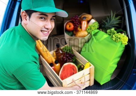 Asian Delivery Man In Green T-shirt Delivering Food, Fruit, Joice And Vegetable To Home - Online Gro