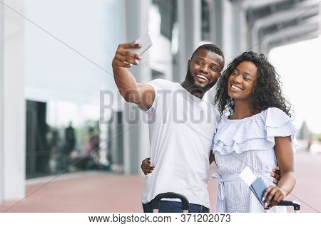 Honeymoon Memories. Happy Romantic Black Couple Taking Selfie Near Airport Terminal, Ready For Trave