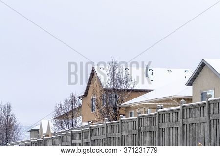 Snowy Houses On A Scenic Suburb Neighborhood Against Cloudy Sky In Winter