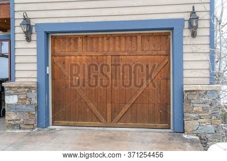 Brown Wood Garage Door With Blue Frame Flaned By Wall Mounted Vintage Lanterns