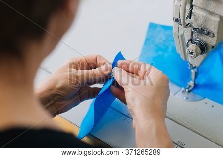Stepwise Stitching Of Blue Fabric Medical Masks On A Sewing Machine. A Close Up Of An Industrial Sew