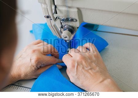 Stepwise Stitching Of Blue Fabric Medical Masks On A Sewing Machine. A Close Up Of An Industrial Sew