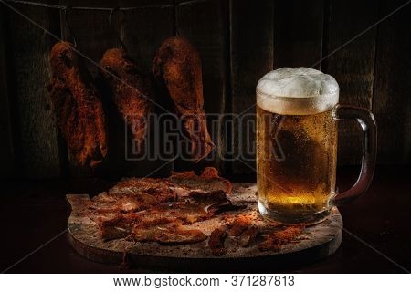 Meat smoked jerky - raw meat . Close up view on tasty sliced Chicken basturma with pint of beer on a wooden board against a wooden background in a composition with spices. Pastirma. Banner Beer snack