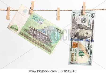 Uzbek Sum And American Dollars Hang On A Rope On A White Background. Money