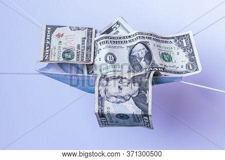 Medical Face Mask And Money On A Light Blue Background. World Coronavirus Epidemic And Economic Loss