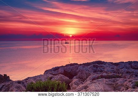 Beautiful Colorful Sunrise At The Sea With Dramatic Clouds, The Sailing Boat And Sun Shining