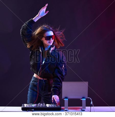 Stylish Dj Girl With Headphones And Glasses On The Bomber Jacket Mixes The Music At The Party And Ne