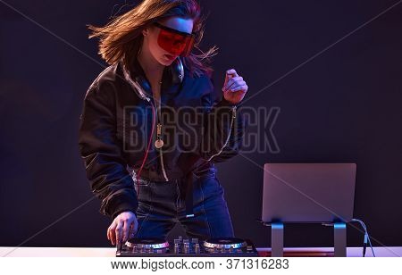 Stylish Dj Girl With Headphones And Glasses On The Bomber Jacket Mixes The Music At The Party And Ne