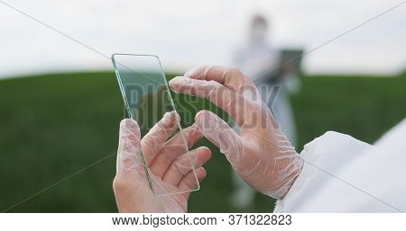 View Over Shoulder Of Farmer Ecologist In Protective Suit Tapping On Glass Transparent Screen. Close
