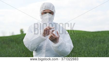 Caucasian Man Scientist In Protective Costume Standing In Field, Tapping On Glass As On Screen Of Fu