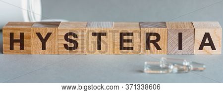 Word Hysteria. Hysteria Text On Wooden Blocks. In Front Of A Row Of Cubes Are Ampoules, In The Backg